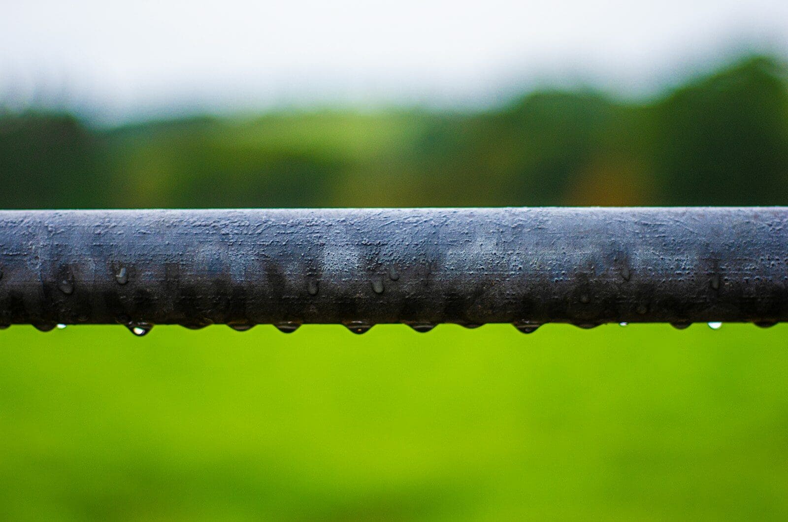 A close up of a metal bar with a green field in the background